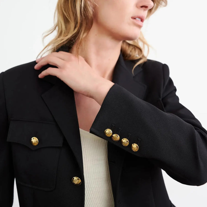 Soft structured shoulder pads. Chest flap patch pockets. Flap patch pockets. Signature crest buttons in gold at front and sleeve. Seaming details for shape. Interior chest pocket. Back vent. Fully lined.