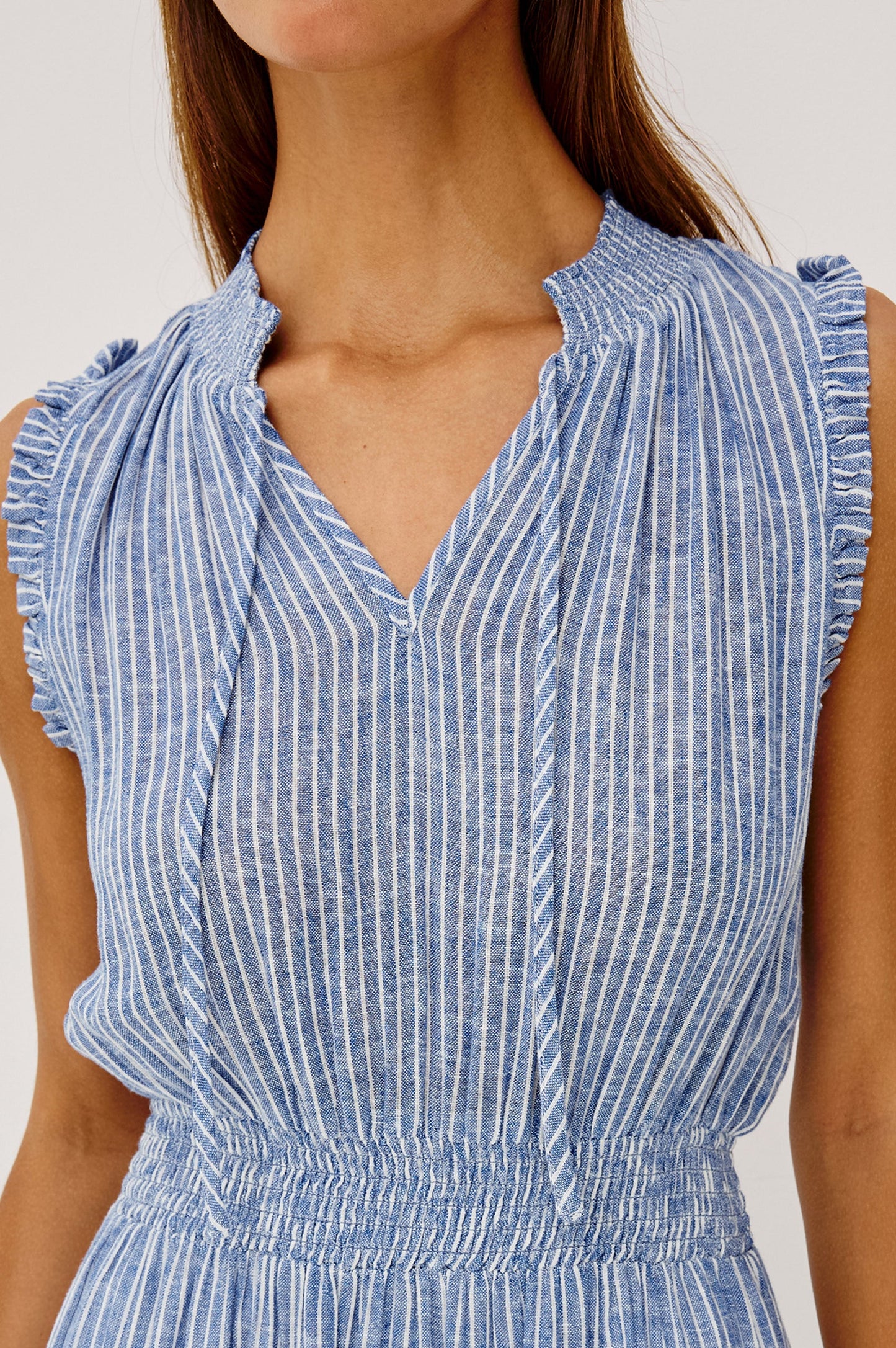 The Alessi is a luxe, lightweight linen midi dress with a relaxed fit, a split V-neckline with self-ties, a smocked waist, ruffle trim, and full lining.