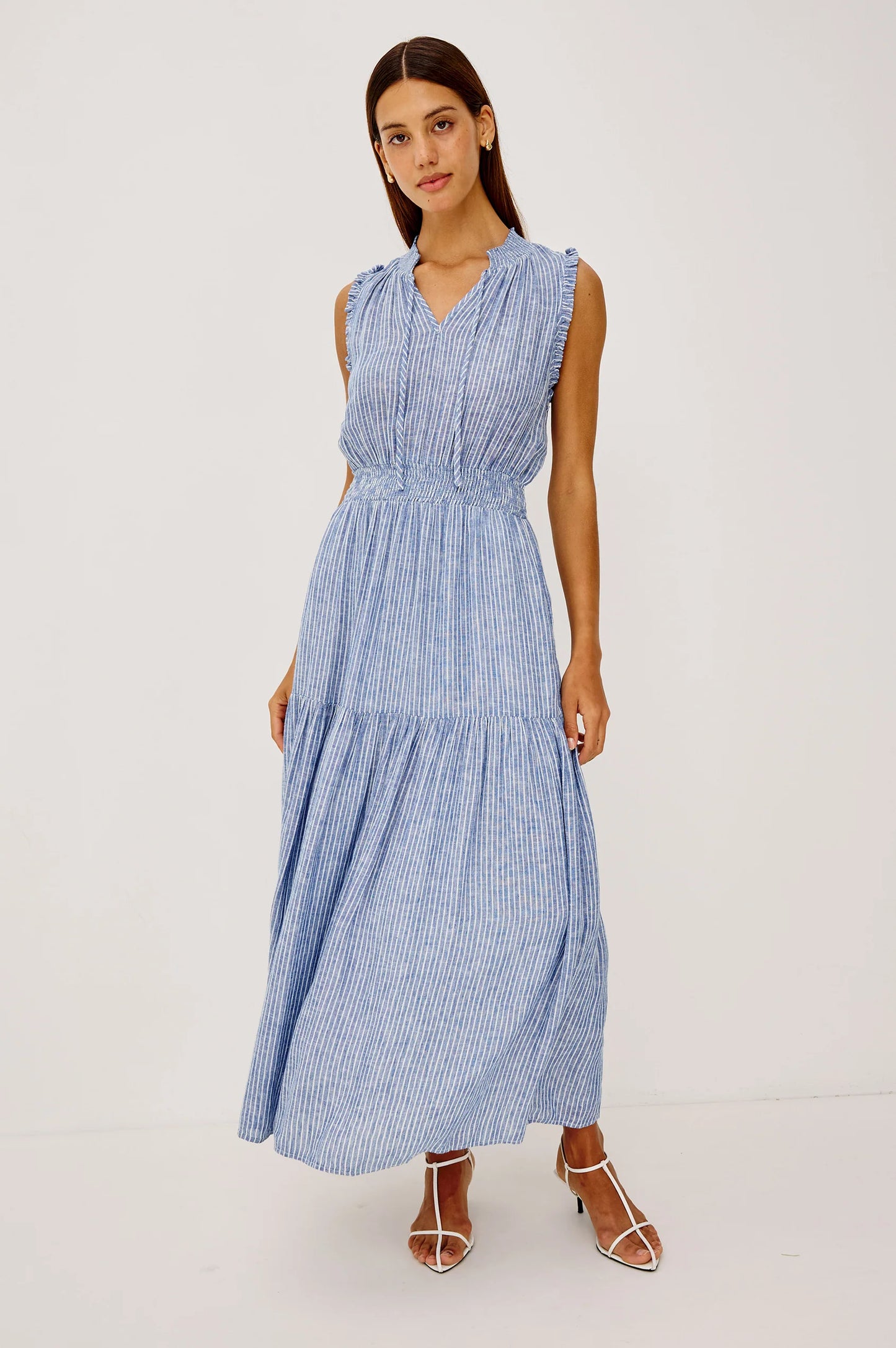 The Alessi is a luxe, lightweight linen midi dress with a relaxed fit, a split V-neckline with self-ties, a smocked waist, ruffle trim, and full lining.
