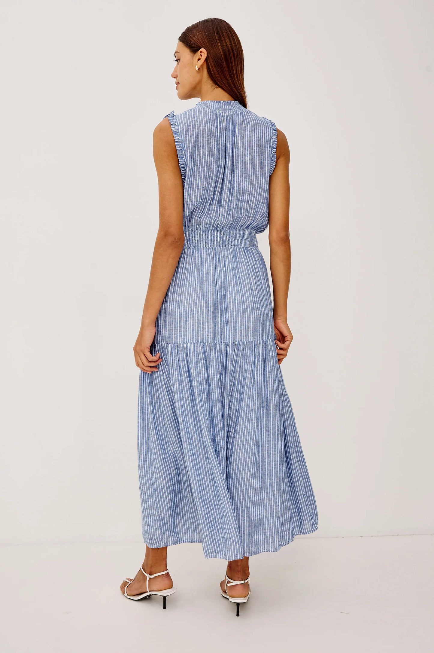 The Alessi is a luxe, lightweight linen midi dress with a relaxed fit, a split V-neckline with self-ties, a smocked waist, ruffle trim, and full lining.