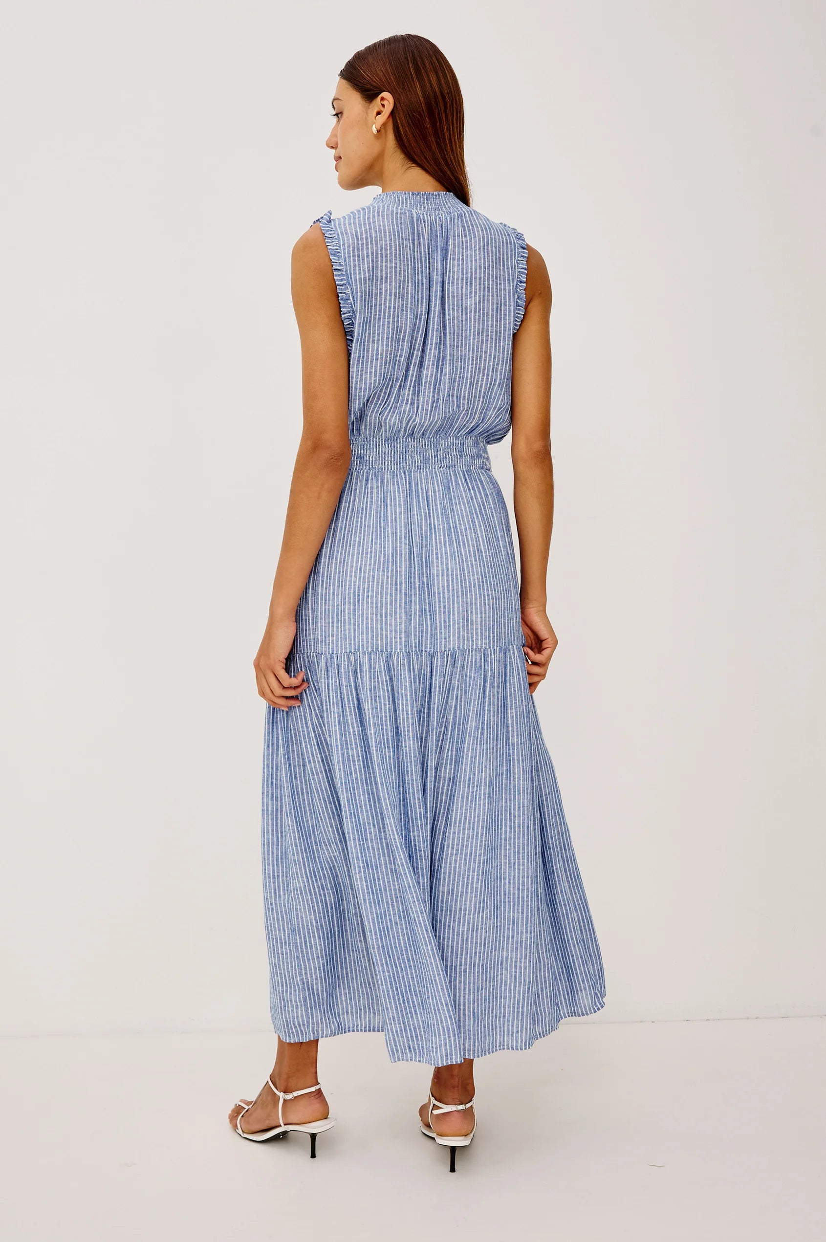 The Alessi is a luxe, lightweight linen midi dress with a relaxed fit, a split V-neckline with self-ties, a smocked waist, ruffle trim, and full lining.