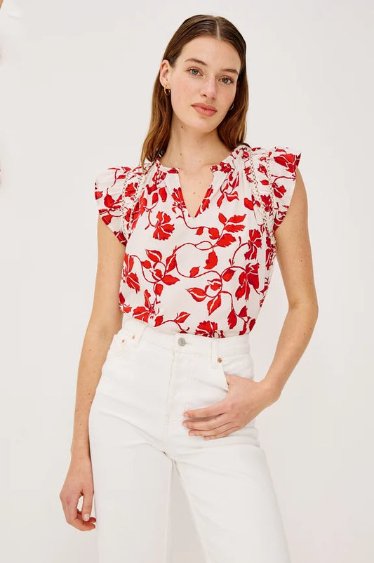 Woman wearing white and red floral blouse with white pants