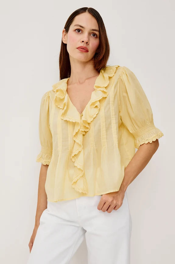 Brunette wearing yellow ruffle blouse with white pants