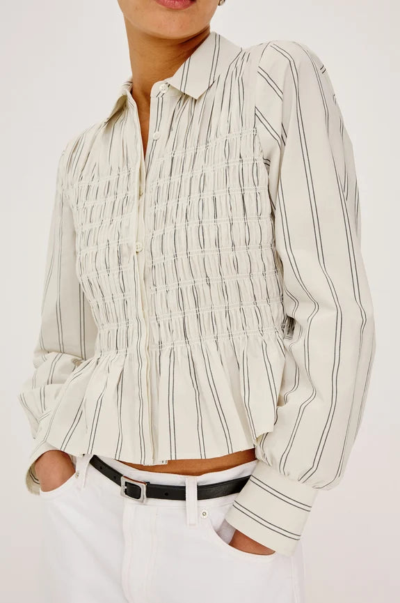 Woman wearing white and ivory peplum top with black belt and white pants