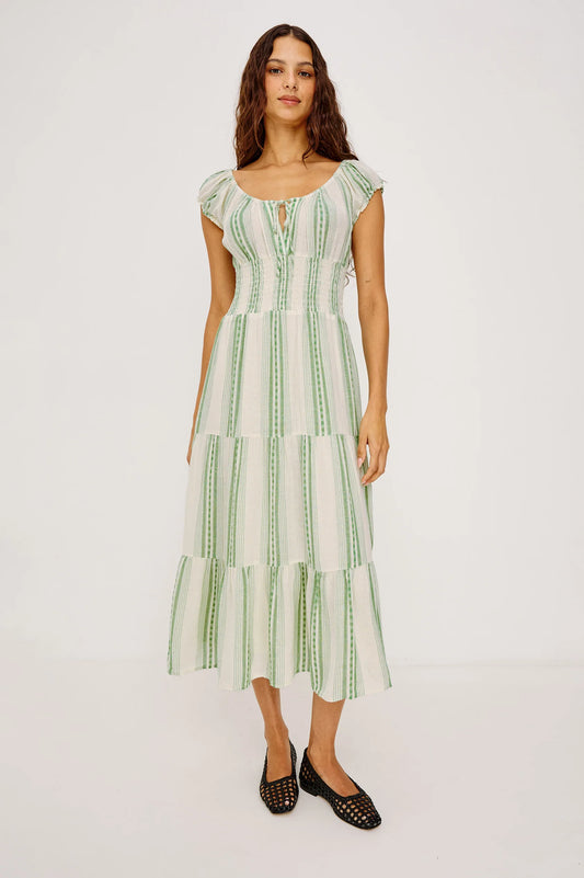 The Alessi is a luxe, lightweight linen midi dress with a relaxed fit, a split V-neckline with self-ties, a smocked waist, ruffle trim, and full lining.