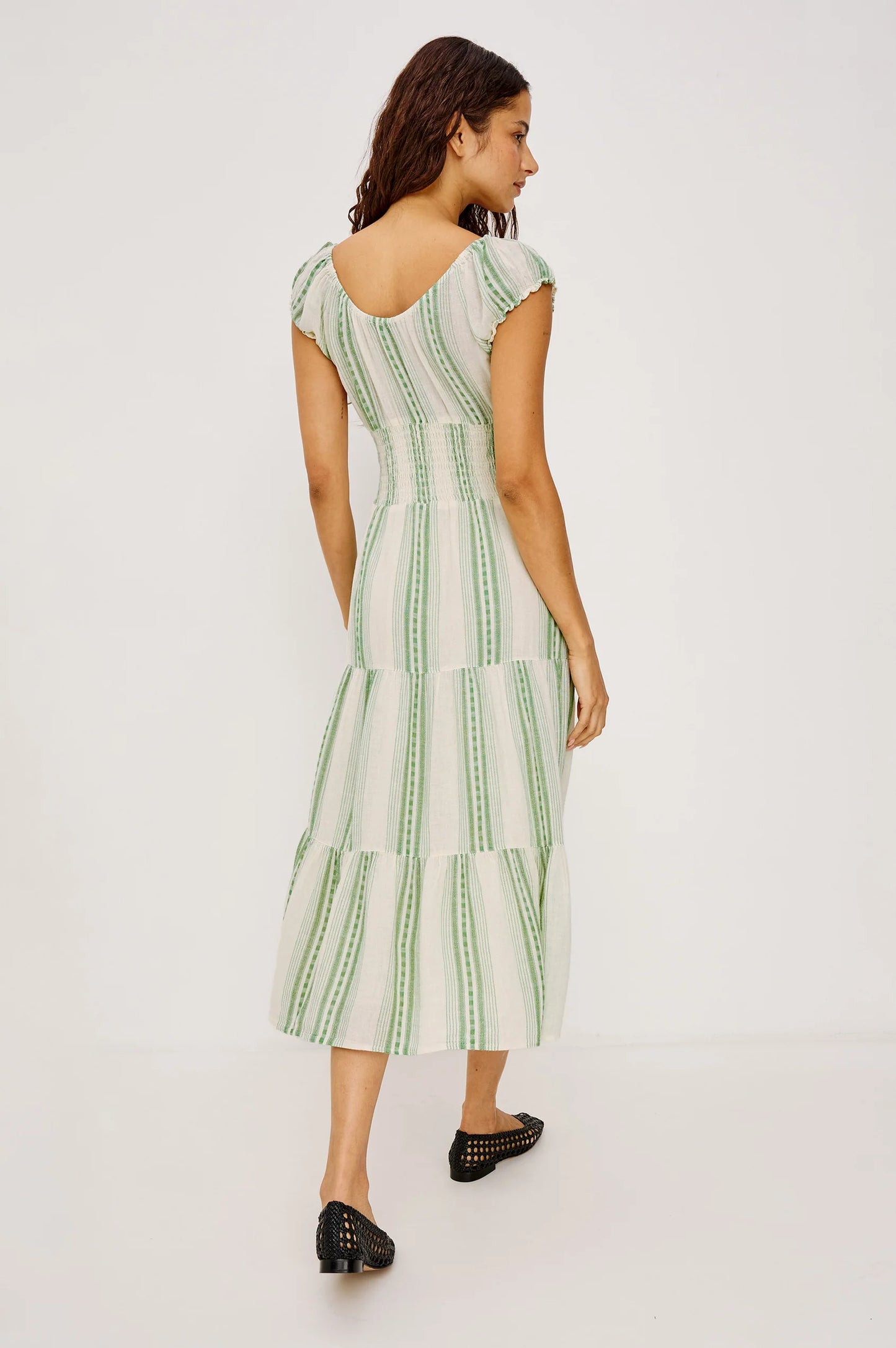 The Alessi is a luxe, lightweight linen midi dress with a relaxed fit, a split V-neckline with self-ties, a smocked waist, ruffle trim, and full lining.