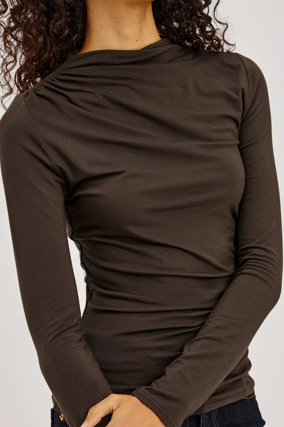 Woman wearing brown mock neck long sleeve fitted top