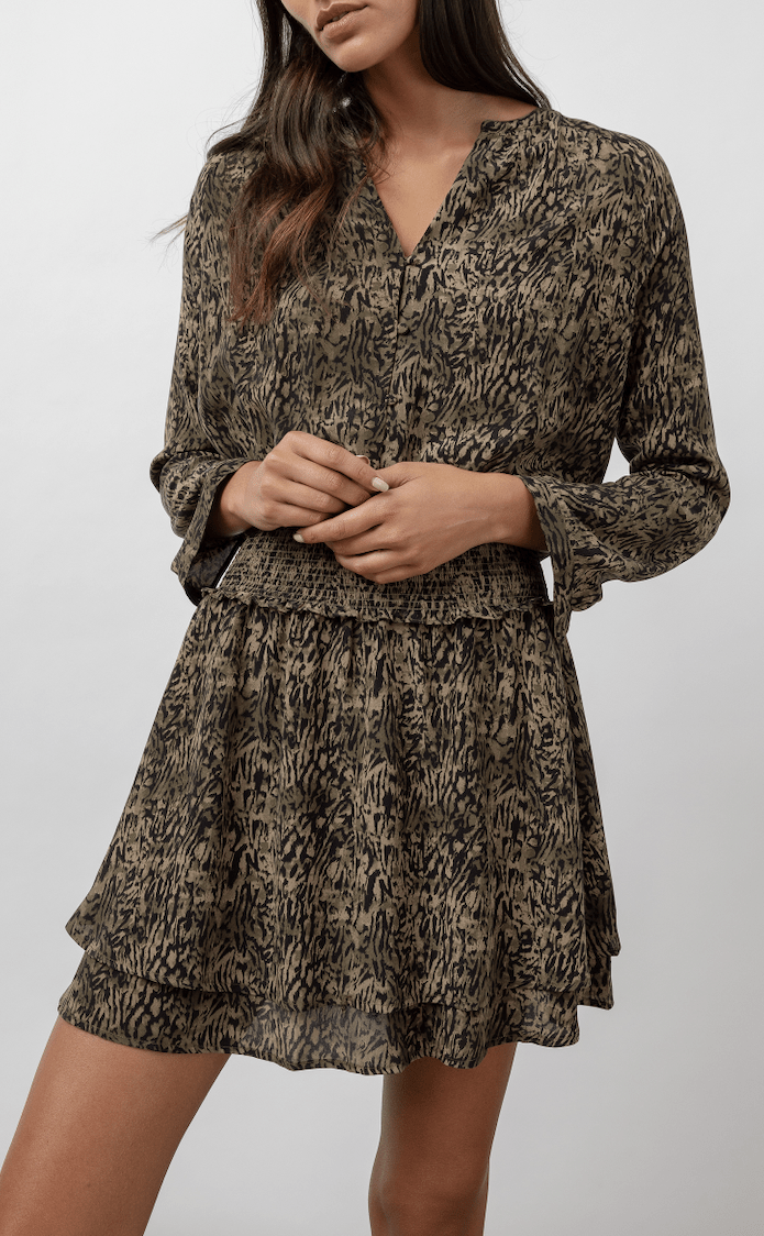 Woman wearing long sleeve mini dress in olive print with smocked waist 