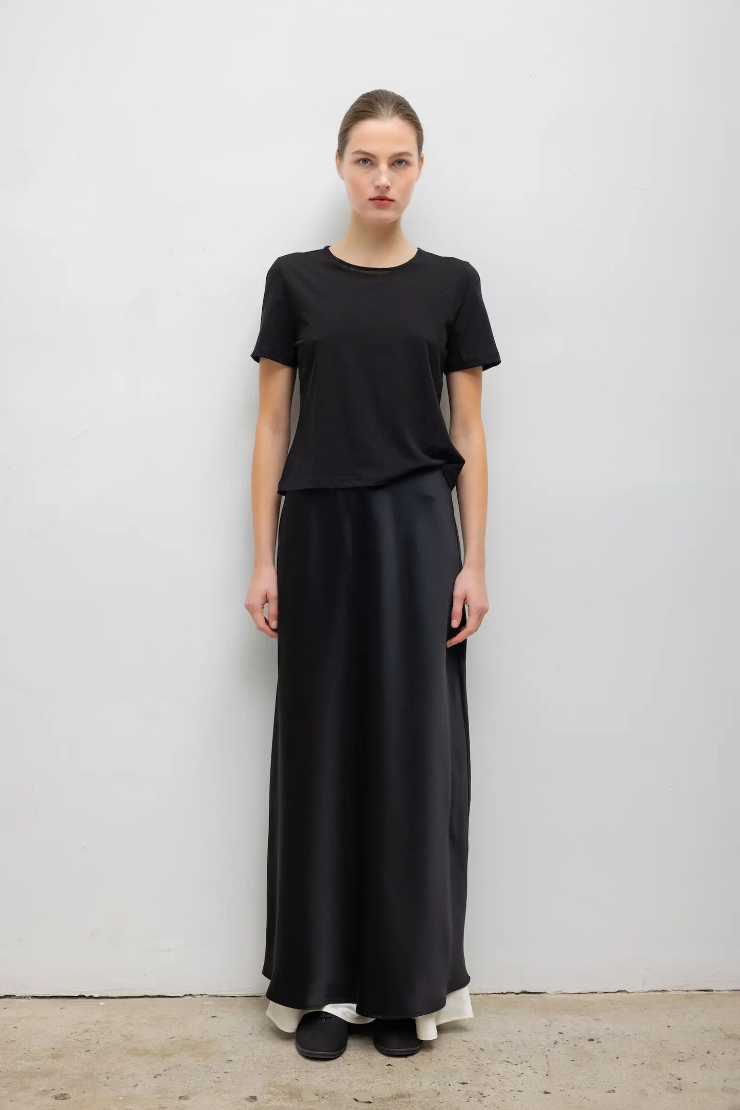 LESET Barb Satin Maxi Skirt in black, styled with a black short-sleeve tee for a monochromatic look.