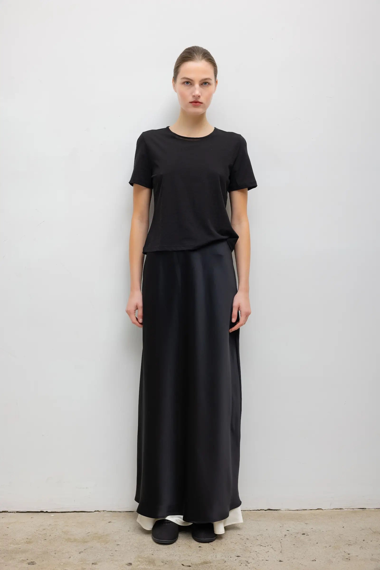 LESET Barb Satin Maxi Skirt in black, styled with a black short-sleeve tee for a monochromatic look.