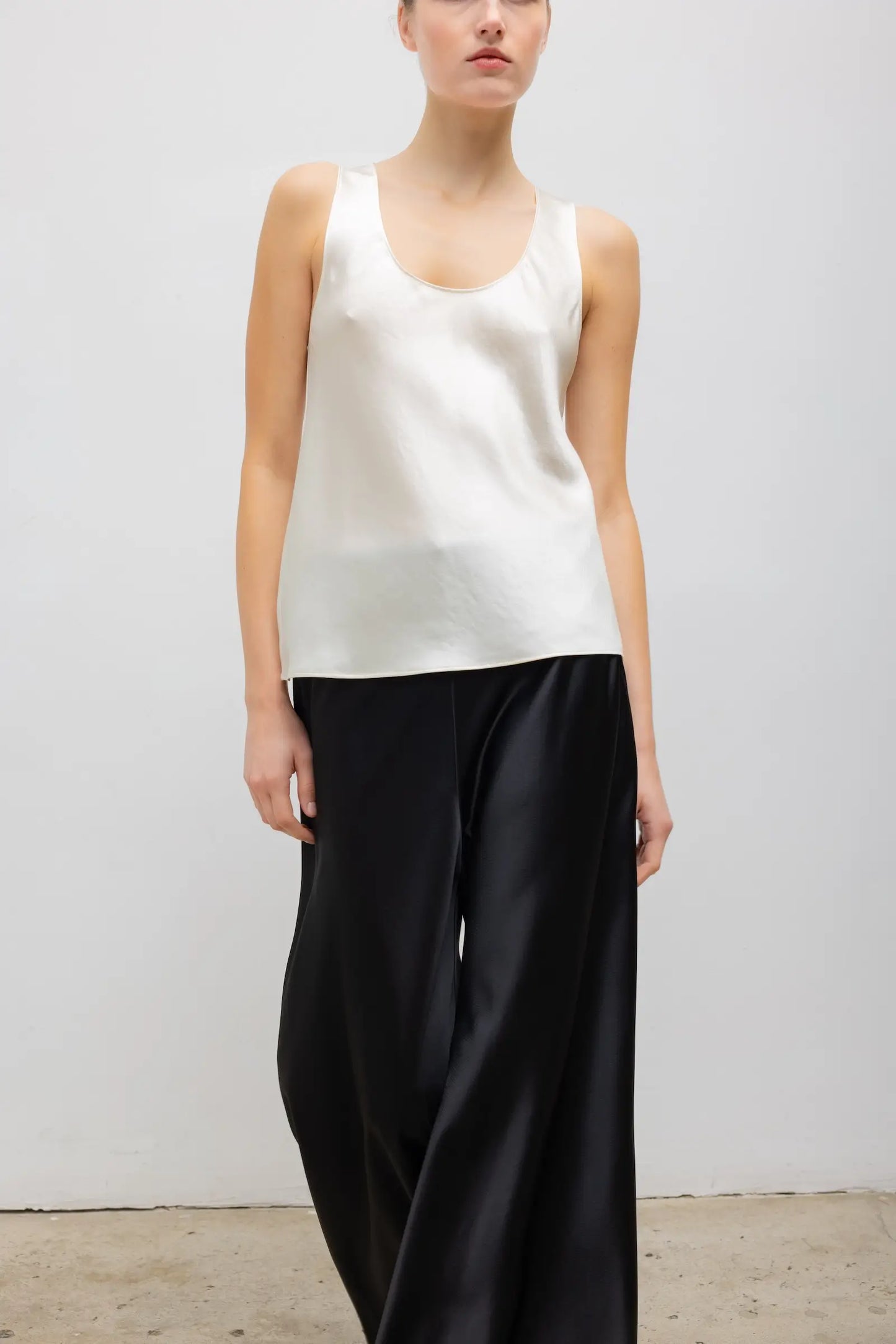 LESET Barb Bias Tank in ivory Japanese satin with scoop neckline, styled with black satin pants.