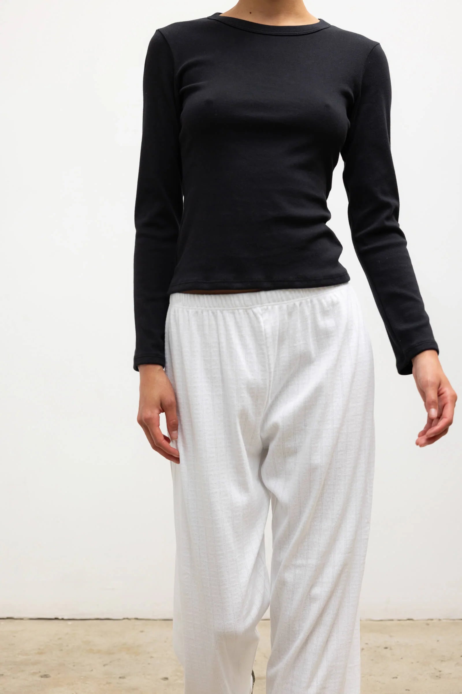 LESET Nando Slim Fit Long Sleeve in Black, a fitted crewneck top in soft baby rib cotton, styled with white pants.