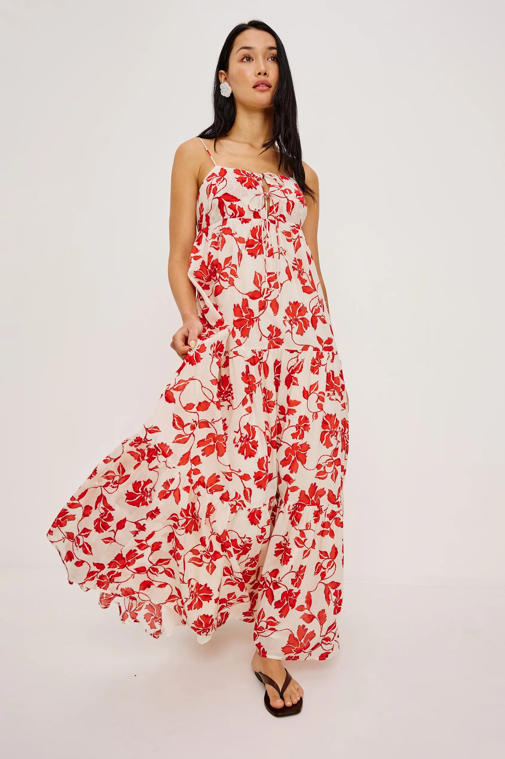 Woman wearing red and white maxi dress with brown sandals and earrings