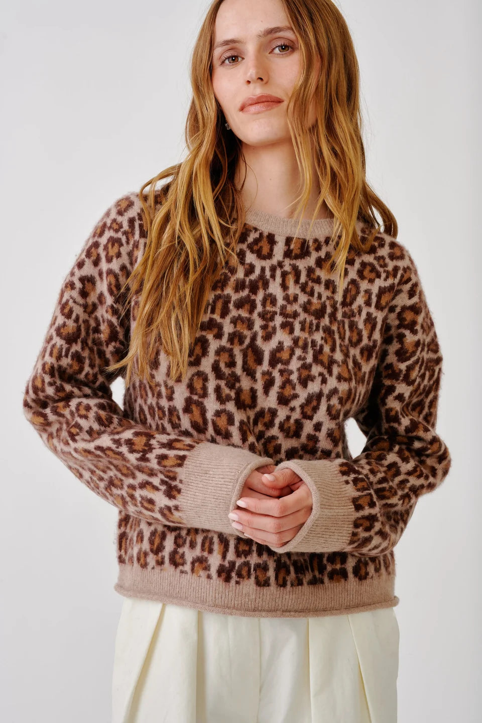 Woman wearing leopard print crewneck sweater and white pants