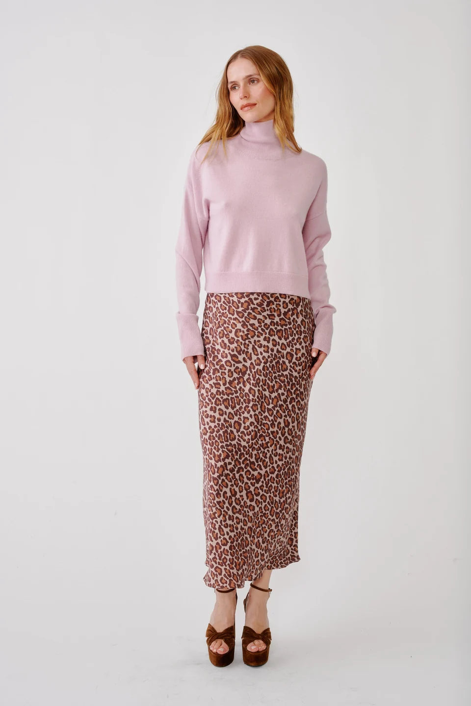 Woman wearing leopard print skirt and pink turtle neck