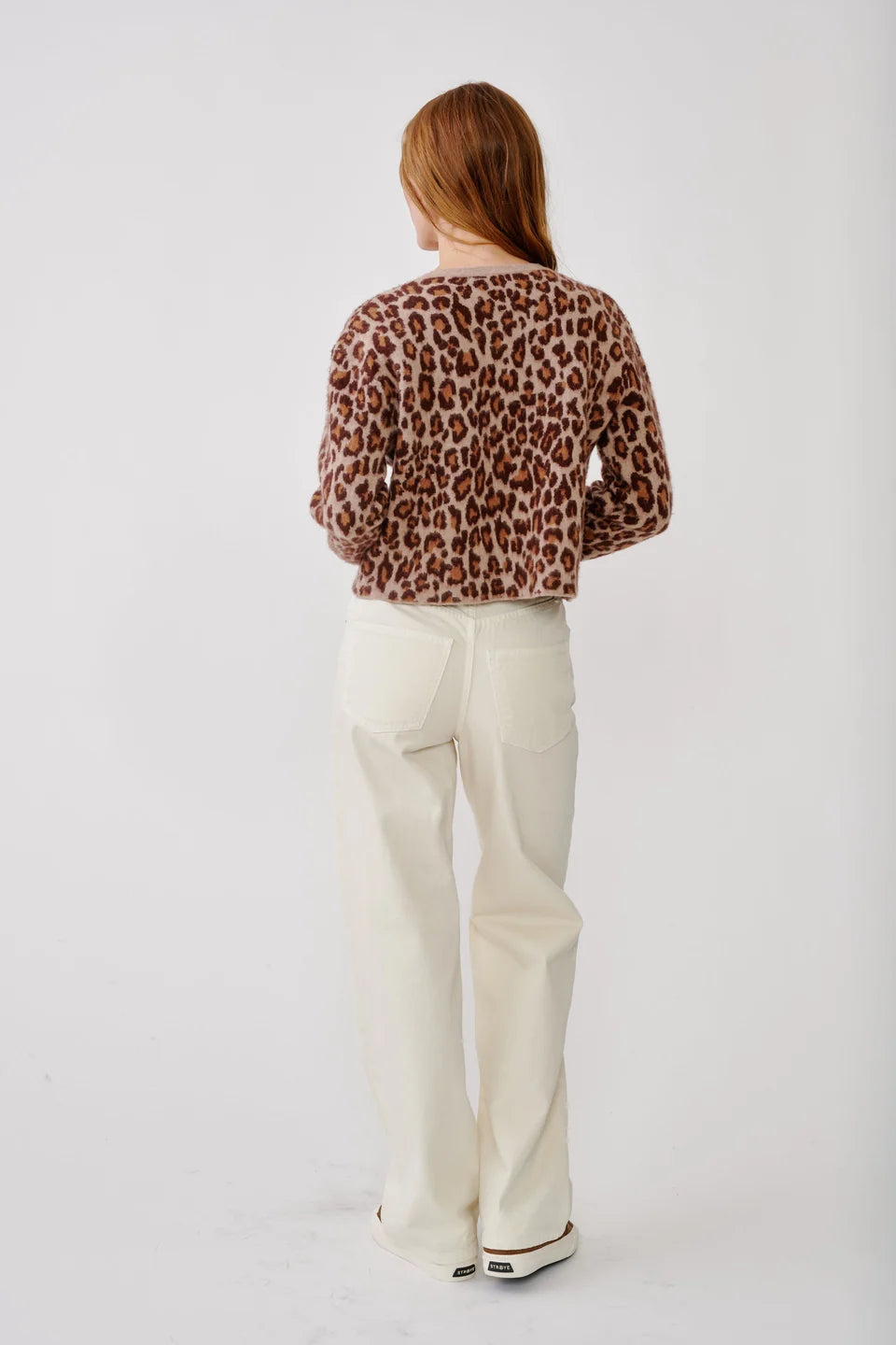 Back of woman wearing leopard cardigan jacket and white jeans 