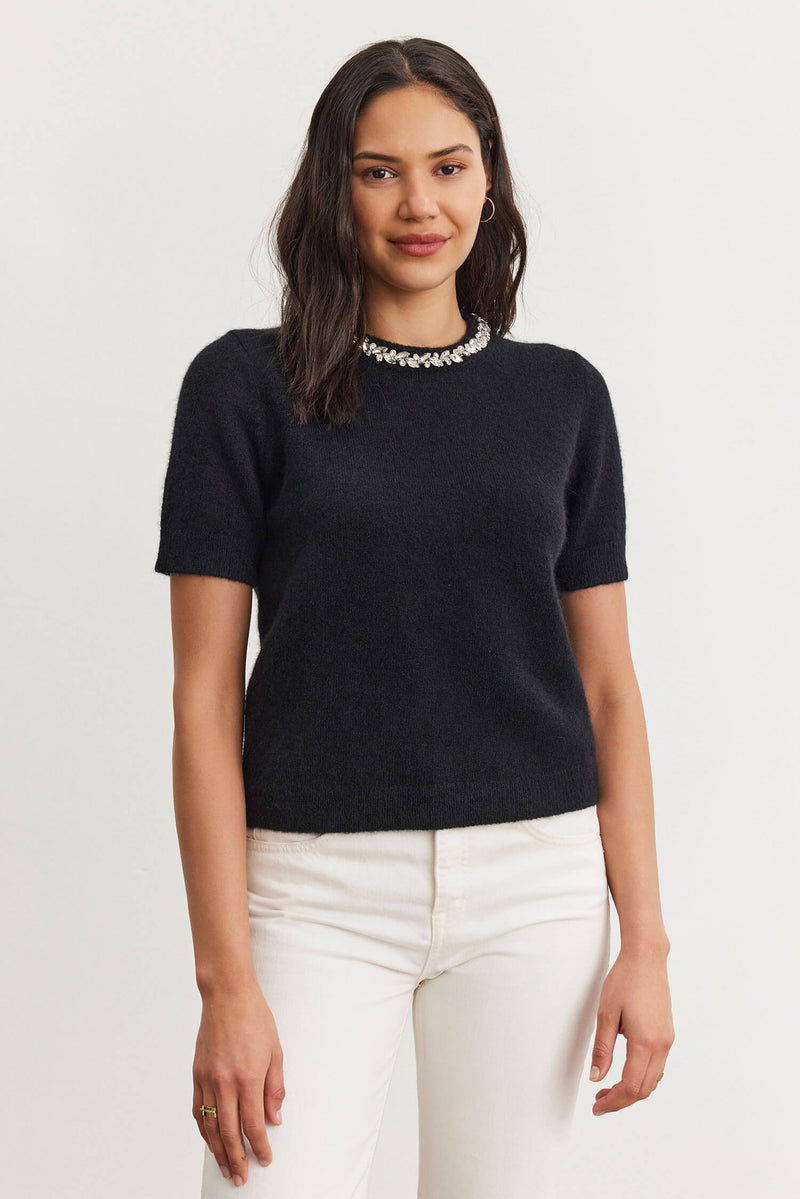 This chic and fashionable sweater features a delicate embellishment on the collar, adding a touch of femininity to any outfit.