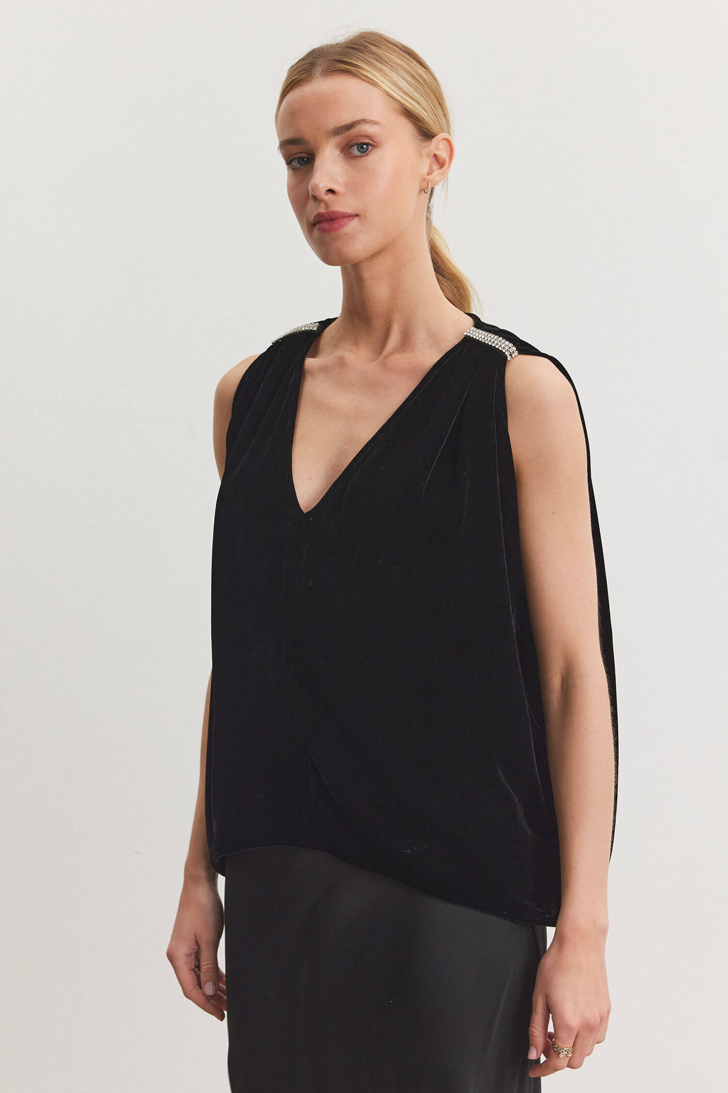 This velvet top features an elegant v-neck, boxy cut, and rhinestone gatherings at the shoulder.   