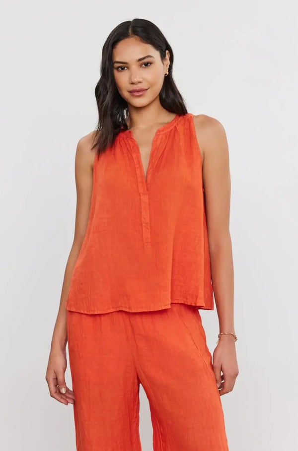 This woven linen sleeveless top features a flattering v-neckline and a relaxed fit, ideal for warm days and relaxed evenings. Complete with a high-low scooped hemline and shirred details on the rear, it's a versatile piece that effortlessly pairs with your favorite shorts or jeans for an easy-going look